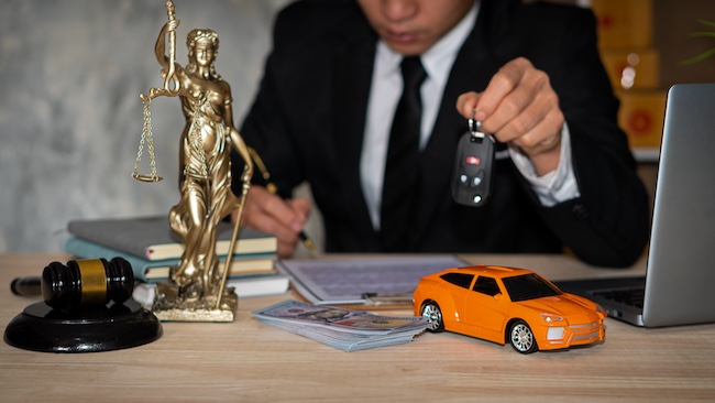 Uninsured Motorist Accident Lawyer reviewing case files with a justice statue on his desk and claim forms.