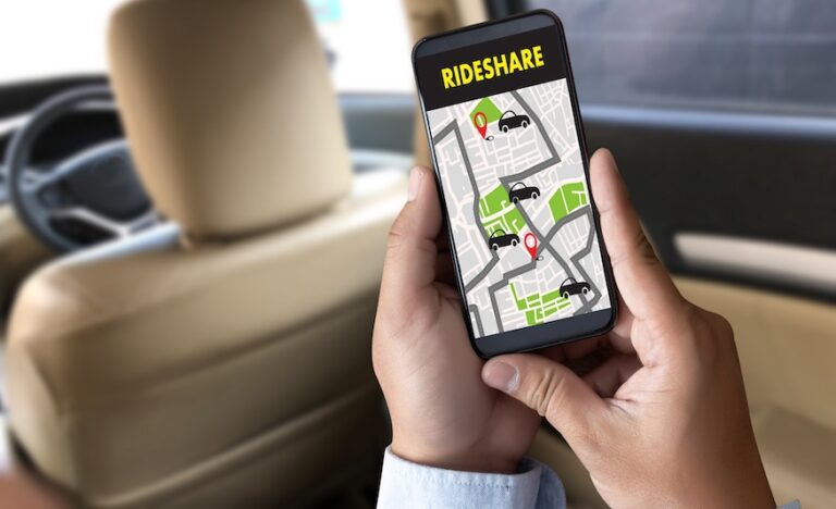 A man is holding up his phone with a rideshare app before being in a rideshare accident.