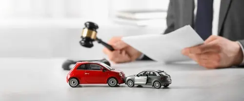 A car accident lawyer sitting at a table reviewing legal documents near two toy cars.