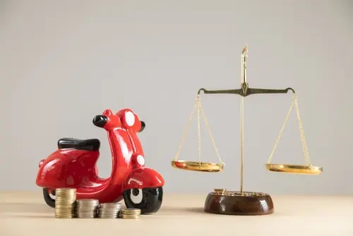 A toy car near a judicial scale to represent a motorcycle accident lawyer representing a client.